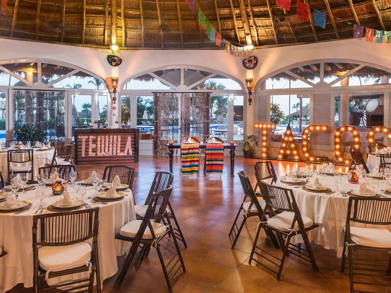 Tavoli rotondi eleganti apparecchiati in uno spazio eventi interno caldo e raffinato.