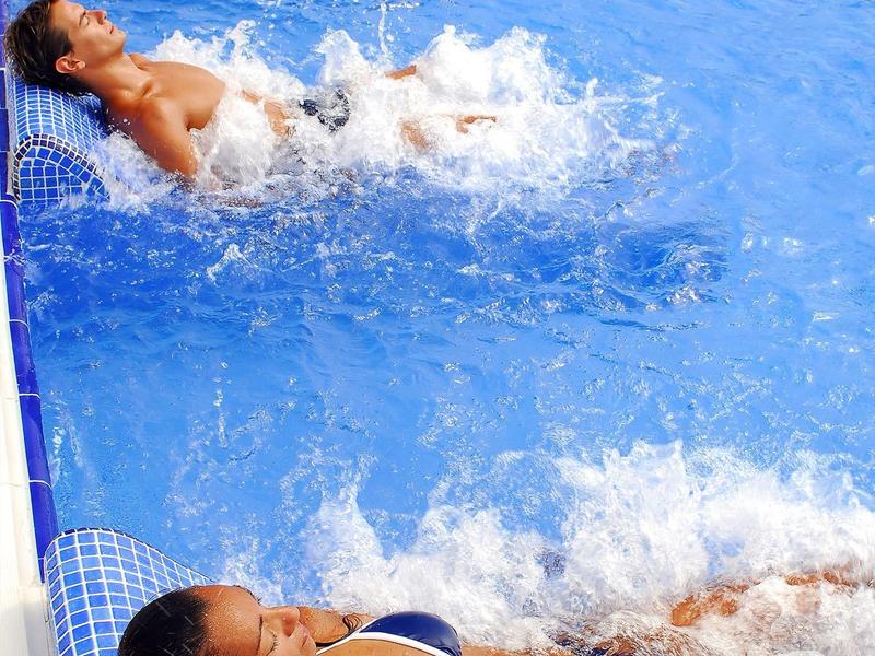 Due donne rilassate in una piscina con getti d'acqua che creano bolle intorno a loro.