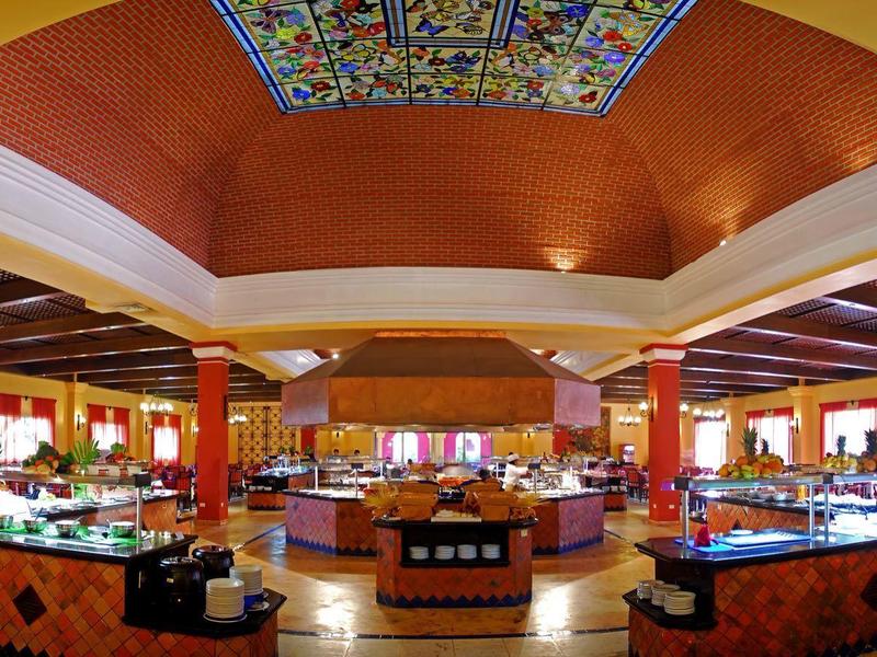 Ampio ristorante dell'hotel con soffitto in legno e pareti arancioni vivaci, pronto per il pasto.