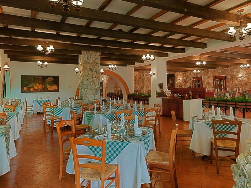 Ristorante luminoso con soffitto a travi di legno, colonne in pietra e tavoli ben apparecchiati.