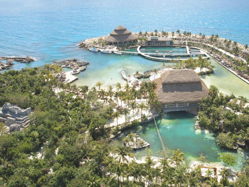 Veduta aerea di un resort tropicale con piscine e vegetazione vicino al mare.