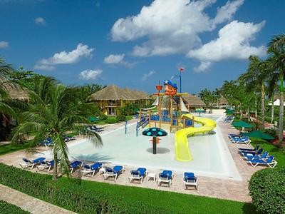 Parco acquatico con piscina, scivoli e lettini in un hotel tropicale.