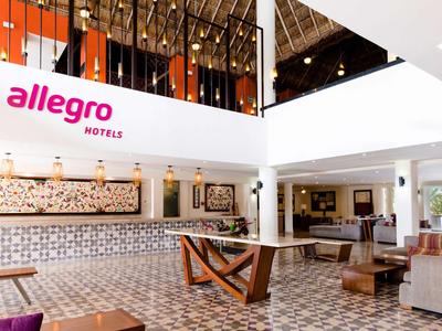 Moderne Hotellobby mit großer Glasdecke, gemustertem Boden und hellem, offenem Raum.