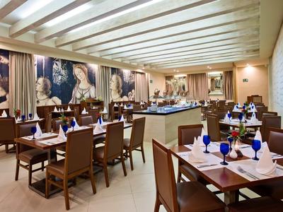 Ristorante elegante con tavoli apparecchiati, bicchieri blu e illuminazione moderna.