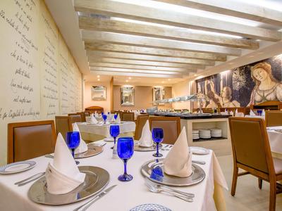 Restaurante elegante con mesas vestidas de blanco, vasos azules y arte en las paredes.