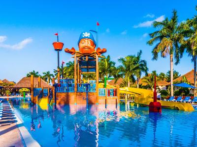 Parque acuático colorido con toboganes y un área de juegos de pulpo en un resort tropical.