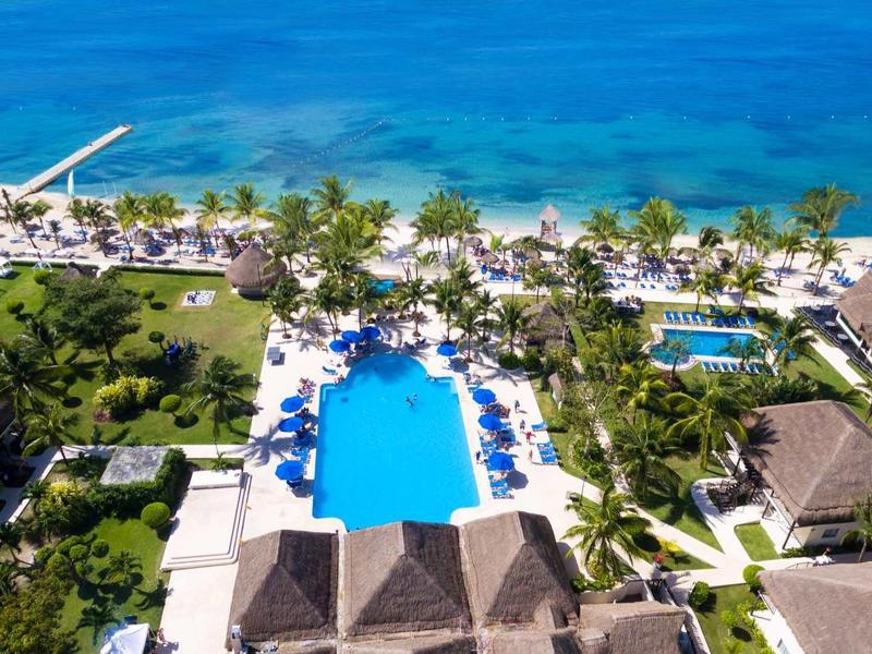 Complesso alberghiero di lusso con grande piscina, palme e vista sul mare