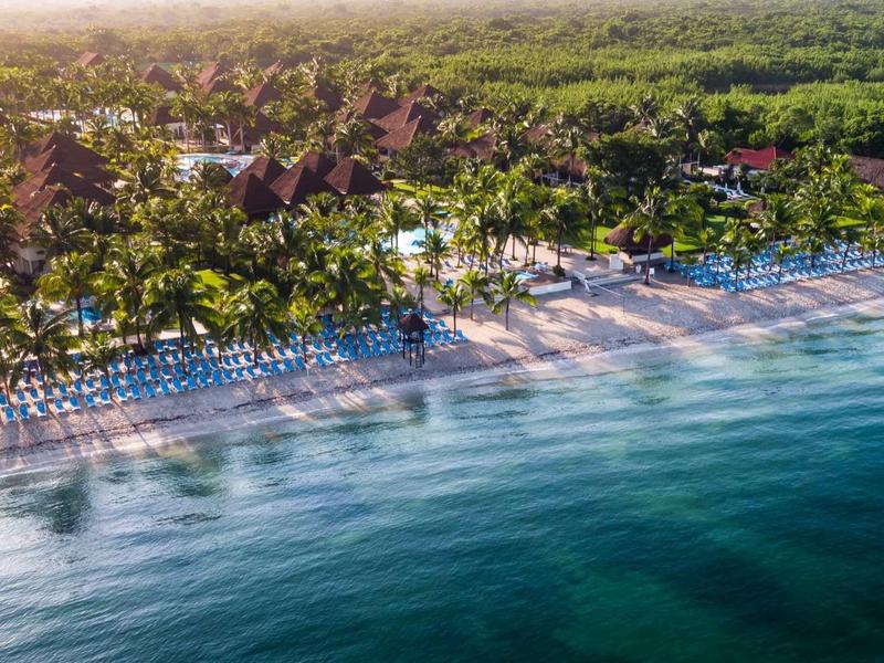 Veduta aerea di una spiaggia tropicale con lettini e palme lungo un resort.