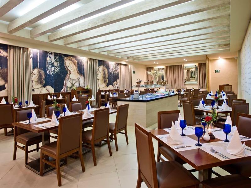 Ristorante elegante con tavoli apparecchiati, bicchieri blu e illuminazione moderna.