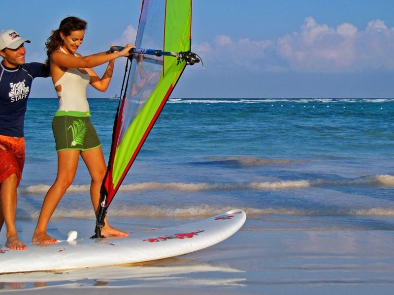 Une femme apprend à faire de la planche à voile sur une plage avec un instructeur.