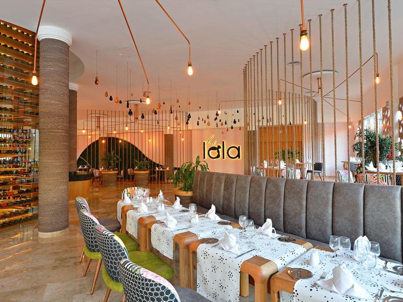 Salle élégante d'un restaurant d'hôtel avec tables dressées et lumière chaleureuse.