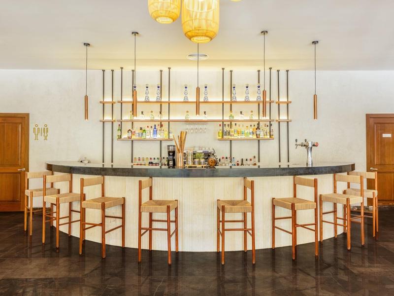 Bar moderne avec tabourets en bois et étagères éclairées.