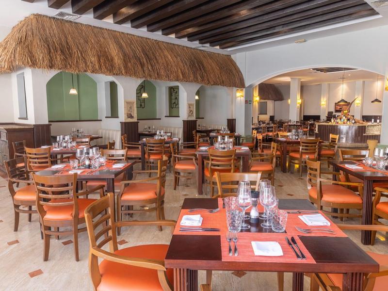 Salle de restaurant spacieuse avec tables en bois et chaises en cuir orange.