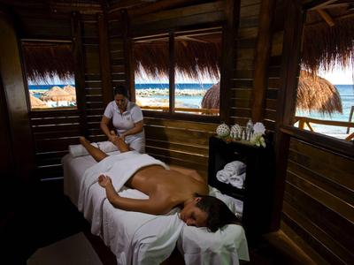 Persoon krijgt massage op een tafel in een houten hut met uitzicht op de zee.