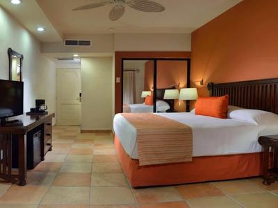 Modern ingericht hotelkamer met groot bed en warme kleuren.