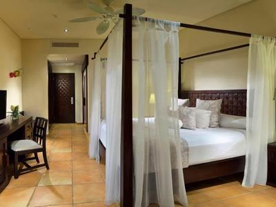 Elegant hotelkamer met hemelbed, bureau, tv en warme verlichting.