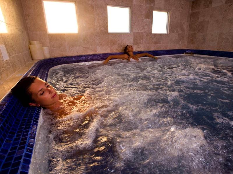 Twee mensen ontspannen in een bruisend bubbelbad in een lichte kamer.
