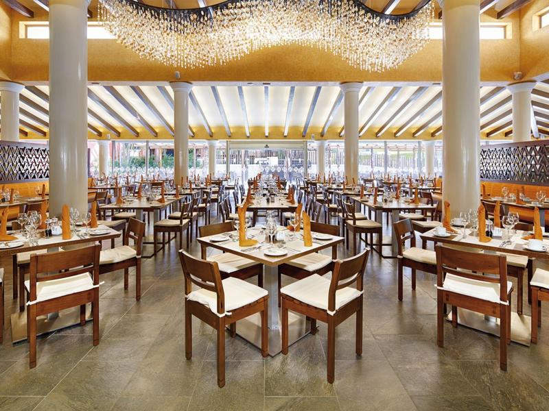 Grande ristorante moderno con tavoli e sedie in legno in uno spazio luminoso e aperto.