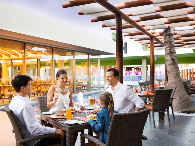 Famiglia che gusta un pasto sulla terrazza di un ristorante moderno in un resort per vacanze.