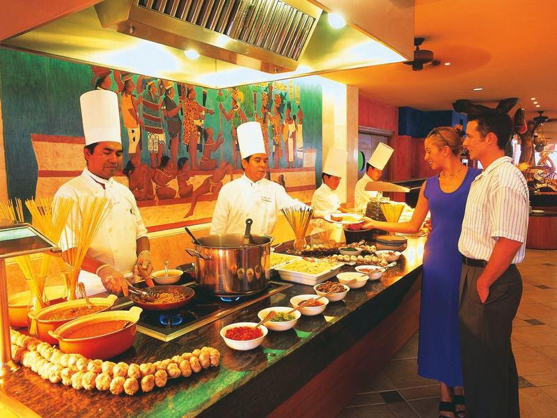 Cuochi preparano cibo a un buffet mentre gli ospiti scelgono e ordinano.