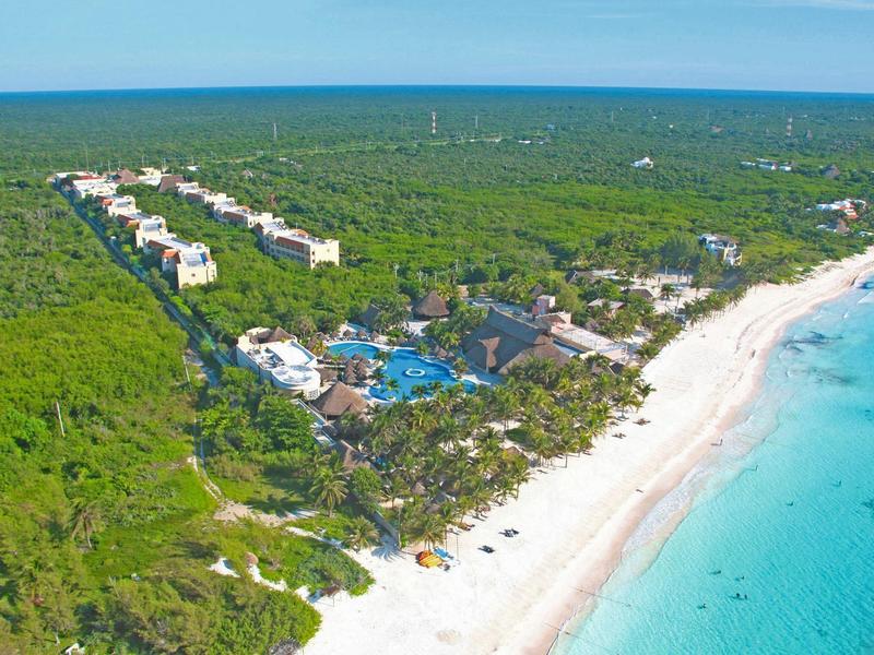 Resort circondato da verde rigoglioso vicino a una spiaggia di sabbia bianca e oceano turchese.