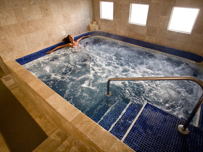 Idromassaggio interno con piastrelle blu e una persona che si rilassa nell'acqua frizzante.