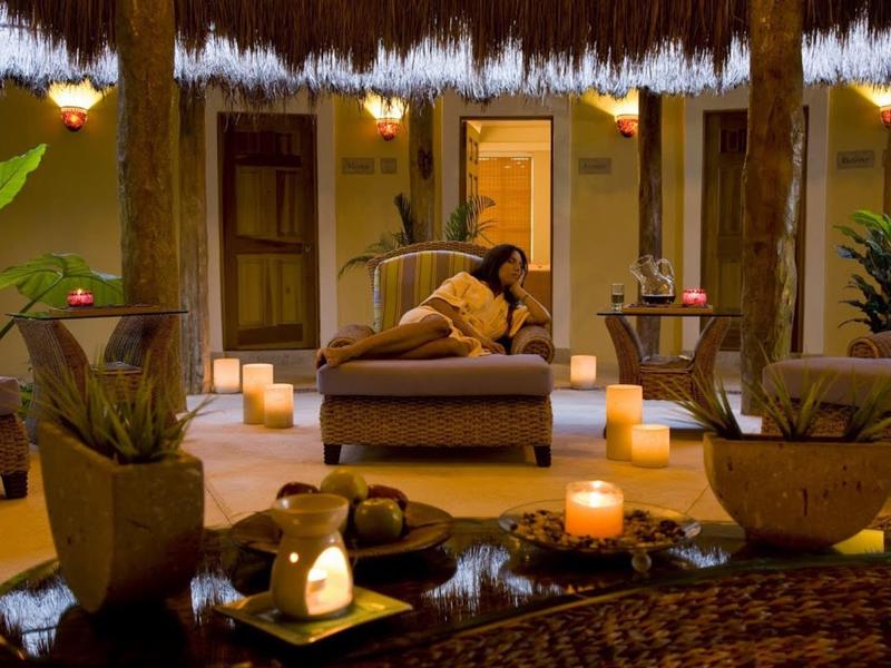 Accogliente area lounge all'aperto con poltrone imbottite, luci di candela e piante tropicali di notte.