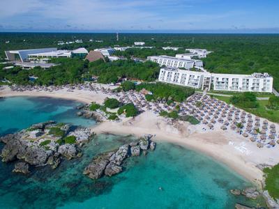 Veduta aerea di un resort sulla spiaggia con edifici bianchi e acqua turchese.