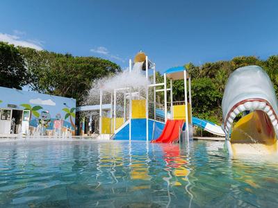 Parco giochi acquatico con scivolo e attrazione scivolo squalo in una piscina sotto il cielo azzurro