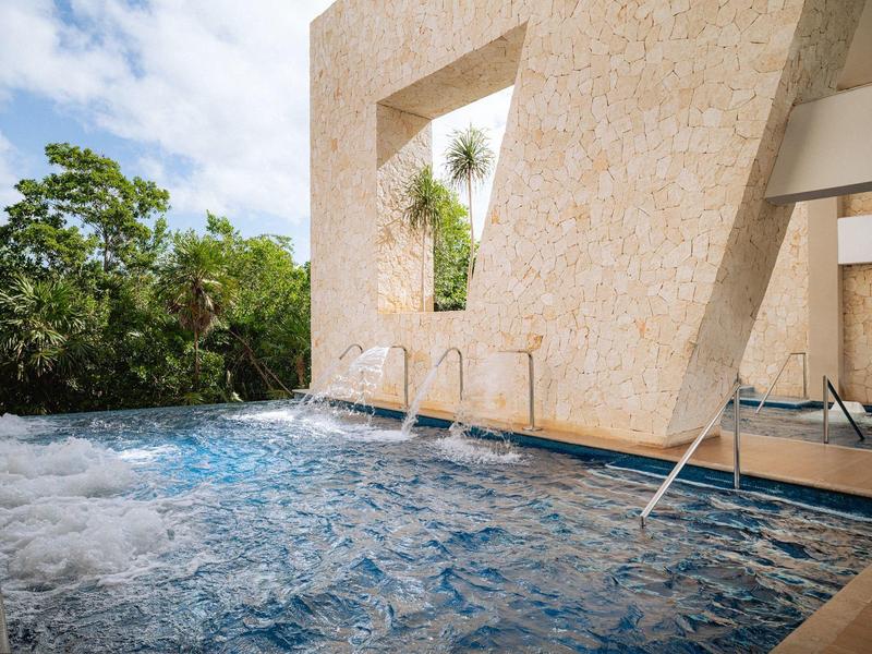Piscina moderna con acqua frizzante e cascata su sfondo naturale