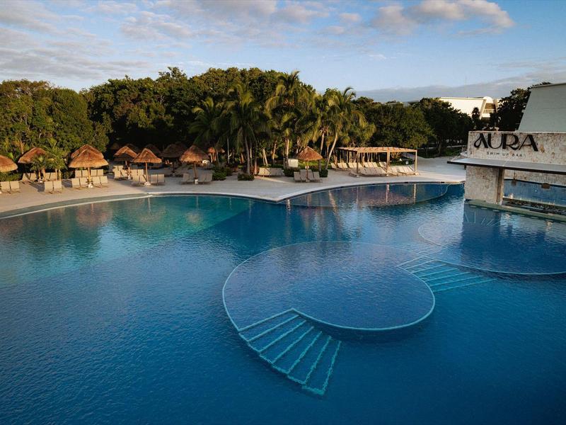 Una grande piscina blu con una scala semicircolare e un'area esterna coperta.