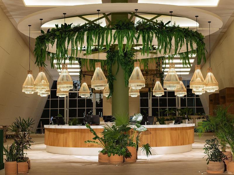 Area moderna della hall dell'hotel con lampade sospese e piante verdi sul soffitto