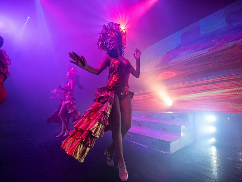 Colorful stage performance with dancers in elaborate costumes and vibrant lighting effects.