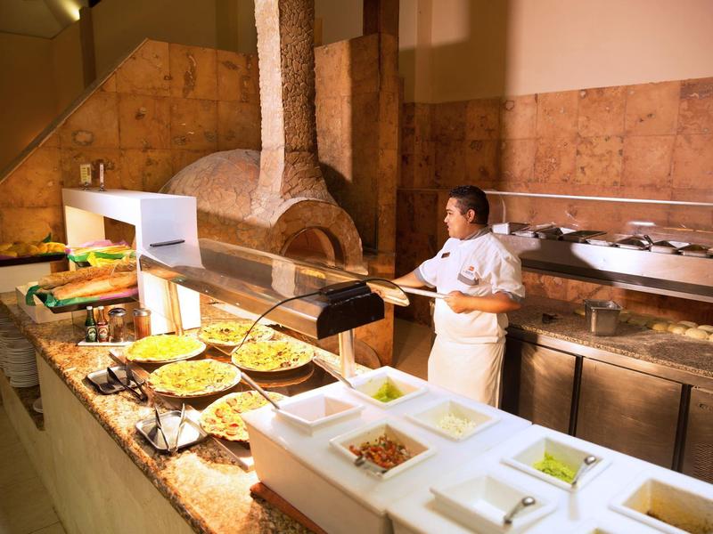 Buffet setup with various dishes and a chef preparing food in a restaurant kitchen.