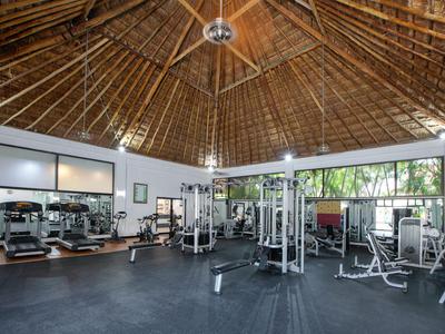 Großer Fitnessraum mit Holzdecke, modernen Trainingsgeräten und Spiegelwänden.