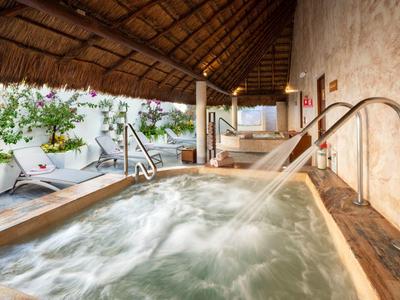 Whirlpool im offenen, überdachten Bereich mit Pflanzen und bequemen Hängesesseln.