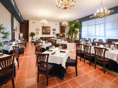 Elegantes Restaurant mit braunen Holzstühlen, weißen Tischdecken und großen Fenstern.