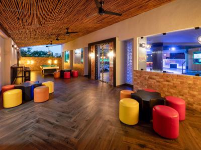 Moderner Innenraum mit bunten Hockern, Holzboden, Decke aus Holzlatten und warmem Licht.