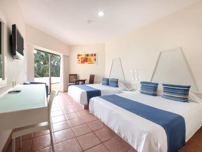 Helles Hotelzimmer mit zwei Betten, Fliesenboden, Balkon und moderner Einrichtung in Weiß und Blau.