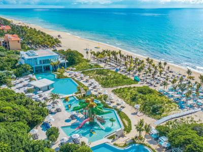 Hotel complex with pool, sun loungers, and direct access to sandy beach by turquoise sea.
