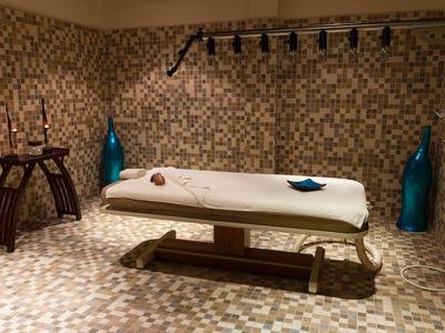 A serene spa room with a white massage table and decorative tiled walls.