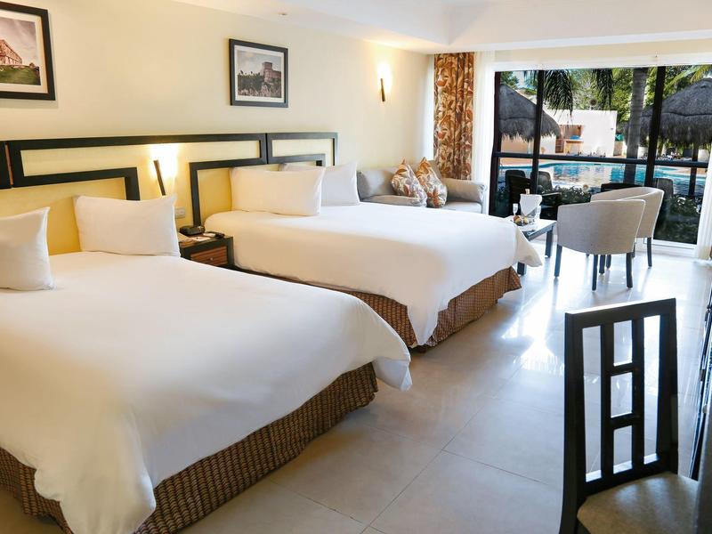 Camera d'hotel moderna con due letti grandi, area salotto e vista sulla terrazza.