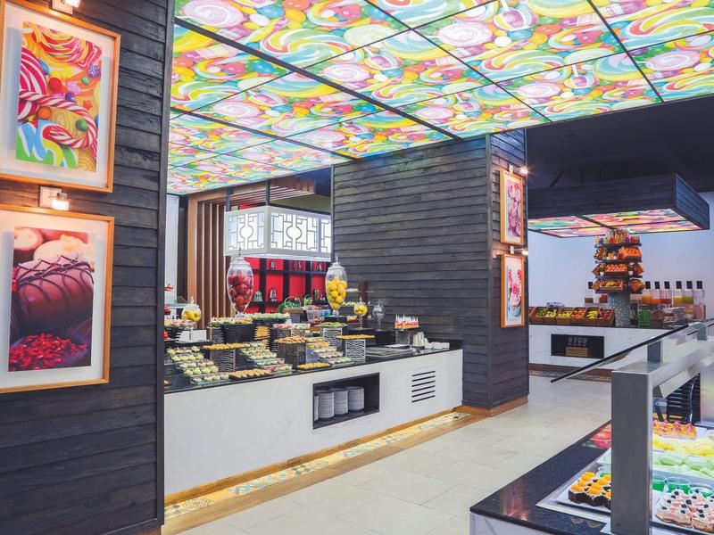 Interno di un bar moderno di succhi e cibo con luci colorate sul soffitto e opere d'arte alle pareti.