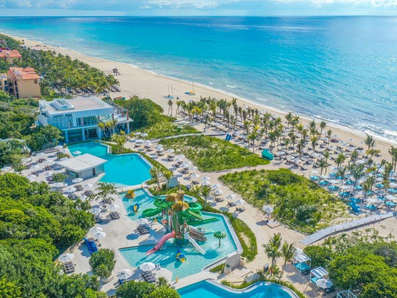 Resort di lusso sulla spiaggia con piscine multiple, palme e accesso diretto al mare.
