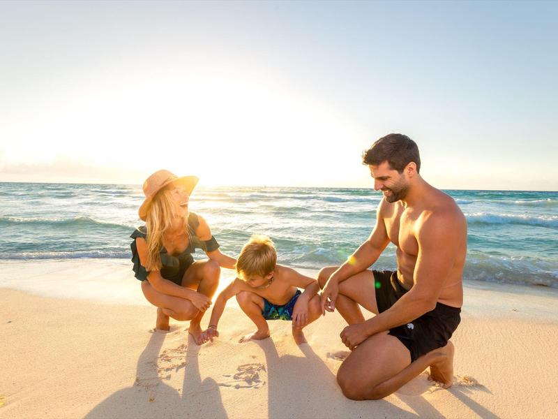 Famiglia con due bambini che giocano su una spiaggia soleggiata vicino al mare.