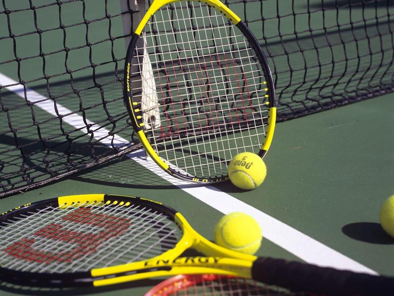 Racchette e palline da tennis gialle sul campo vicino alla rete.