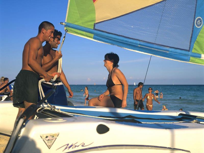 Gruppo di persone che si rilassano su una barca a vela con vela colorata al mare.