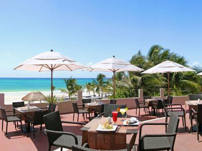 Terrasse eines Restaurants mit Sonnenschirmen und Blick auf den Ozean bei klarem Himmel