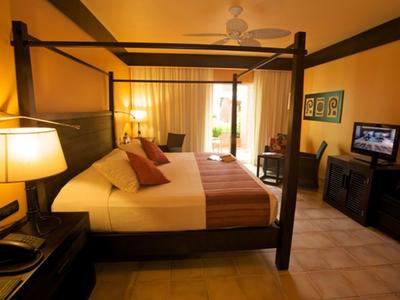 Camera accogliente con letto a baldacchino, illuminazione calda e TV in una stanza d'hotel.