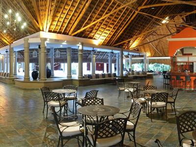 Offener Hotel-Pavillon mit Stahltischen und Stühlen unter einem hohen Holzdach.